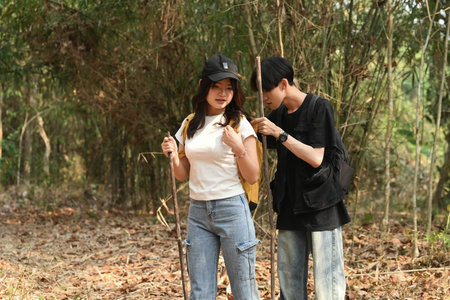 Young LGBT man searches for belongings in partner's bag while hiking.の写真素材