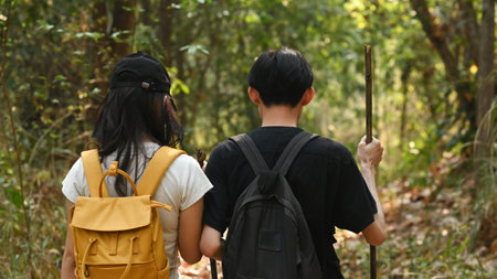 Rear view of Lovely Young couple dating in the woods, trekking outdoors, and doing leisure activities together.の写真素材