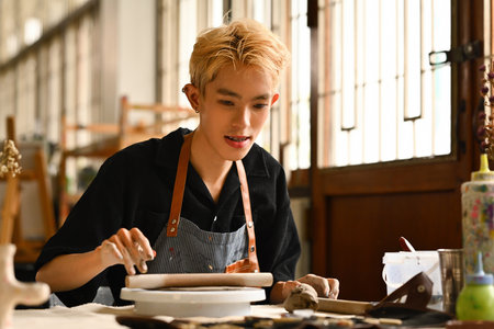 A Teenage LGBT boy with colored hair working with clay in an art studio, LGBT people's lifestyles and creative leisure activities concepts.の写真素材
