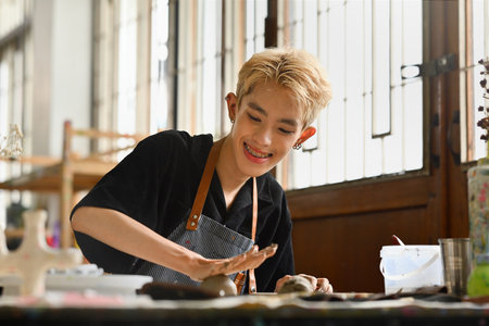 A Happy young LGBT boy enjoys making handcrafted earthenware, molding clay by hand, Creative People Handcrafted Design concept.の写真素材