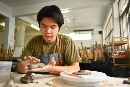 An artist concentrates on shaping clay in a well-equipped studio, showcasing the creative process of...