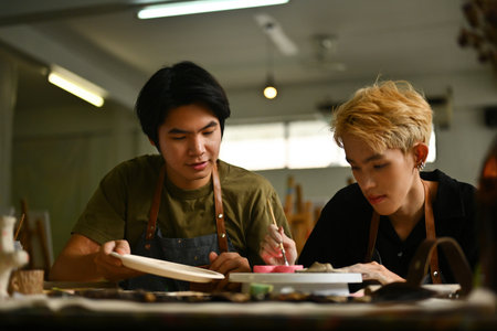Students focused during art class hours, meticulously working on their ceramic projects. The image captures a moment of concentration and creativity in a classroom setting.の写真素材