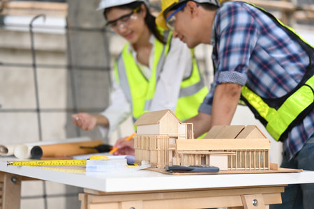 An architectural model is the focal point on a table at a construction site. Two professionals in...