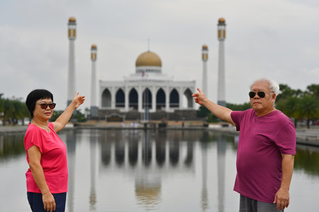 Elderly Asian tourist couple pointing to Central Mosque in Songkhla, Thailand, Lifestyle After Retiree concept.の写真素材