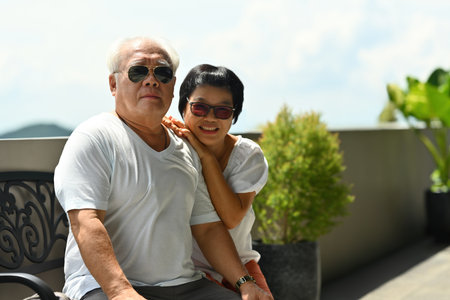 Happy Mature Asian couple embracing, smiling at the outdoors.