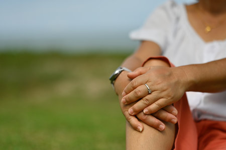 Close-up middle-aged female hands on knees while sitting in a kneeling position.の写真素材