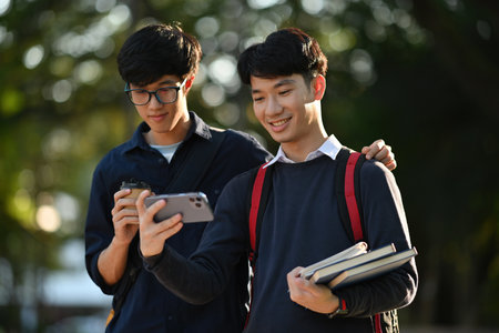 Two Asian male students looking at the phone together and showing excited expressions.の写真素材