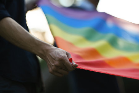 Backlit and close-up photographs of hands spread the rainbow flag, campaign for gender equality and equal marriage.の写真素材