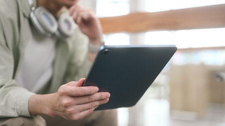 Close-up of Smart Young adult man digital reading on tablet in a cafe, Selective focus on hands.