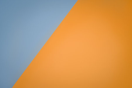 A diagonal division of two solid blue and orange colors creates a minimalist and modern color block design, suitable for backgrounds or creative layouts.の写真素材