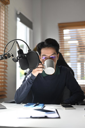 A Focused Podcaster or Podcast Host Enjoying a Coffee Break.の写真素材