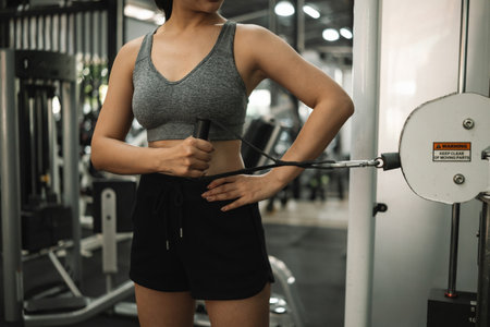 Close-up view of a woman performing rotator cuff strengthening exercise using a cable machine at the...