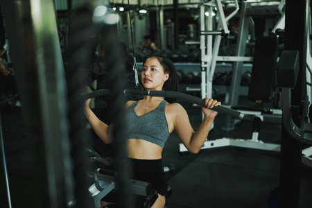 Focused Woman Performing Lat Pulldown Exercise.