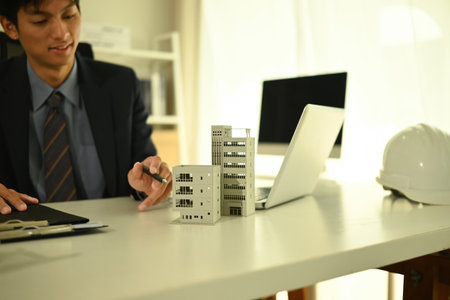 Businessman Planning Real Estate Project with Building Model, Focused on building model at desk.