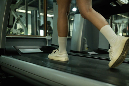Close-up of a womanâs legs walking on a treadmill at the gym. Focus on fitness, routine, and cardio training.の写真素材
