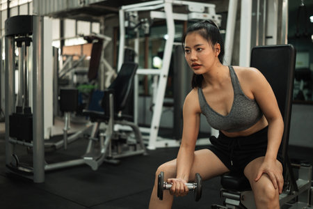 Confident Asian Woman Focused Biceps Curls Workout.