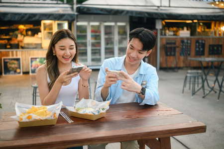 Young Asian Friends Taking Photos While Enjoying Street Food, Capturing Street Food Moments.