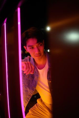 Close-up image of A Young Man Poses in Neon Light at Night.