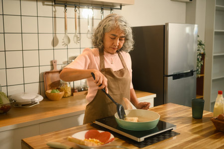 A Old Asian Woman Cooking Breakfast in a Home Kitchen, Concept Senior domestic lifestyle.
