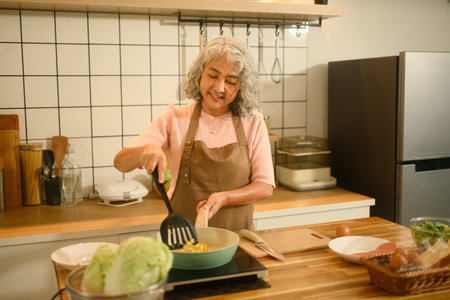 Happy Senior Asian Woman Preparing a Meal in Kitchen.の写真素材