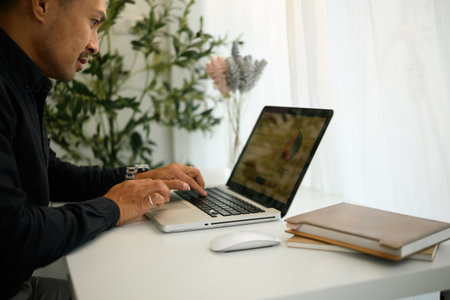 Close-up side view of a mature businessman working on a laptop with charts on screen, Financial Data...