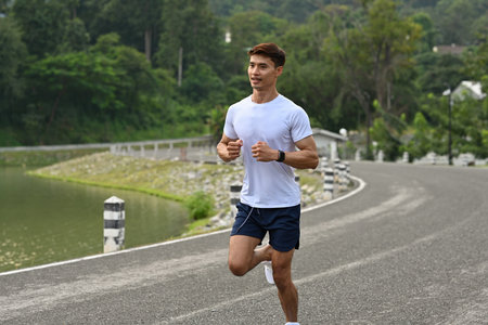 A Runner enjoying a morning jog on a road surrounded by greenery.の写真素材