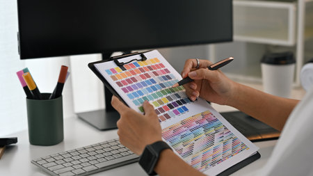 Close-up of hands holding a color chart and pen, Graphic Design and Color Matching.