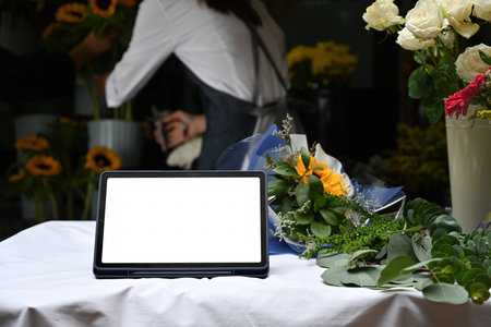 Blank Digital Tablet Screen on Floral Worktable, Digital Marketing Setup at Flower Shop.