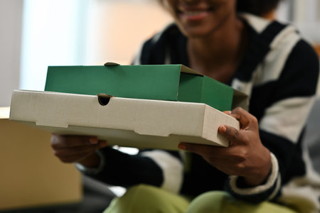Close-up of a woman holding stacked pizza boxes, representing food delivery and takeout service in a...