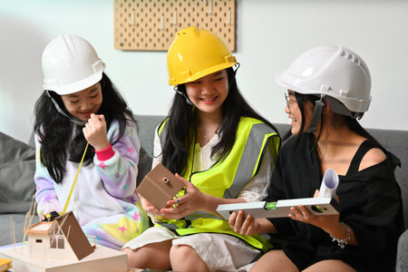 A portrait of three pretty Asian girls wearing a helmet, playing roles as architecture or engineering, for education, career and safety concept.の写真素材