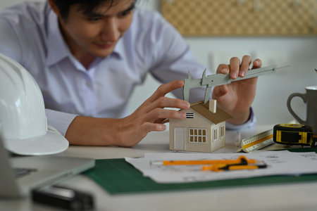 A portrait of an architecture working on a house model,  blueprint with tools and machine on the...