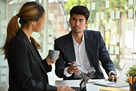 Portrait of serious Asian businesspeople holding cups of coffee, working together on a document and...