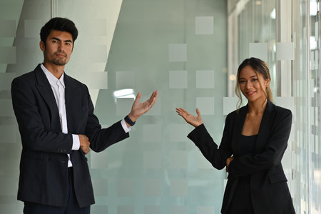 A portrait of Asian businesspeople standing in a workplace pointing  hands to the side, for business...