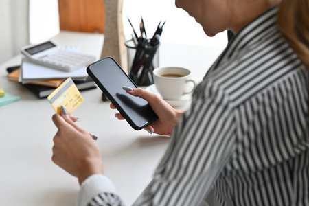 Shoulder view of woman using a credit card for online shopping, e-commerce, internet banking,...