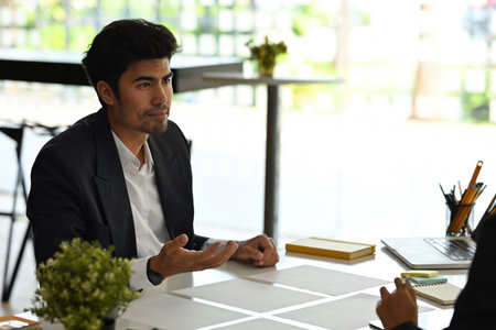 A portrait of good looking Asian businessman working with another colleague on a paperwork and tablet in the office, for business and technology concept.の写真素材