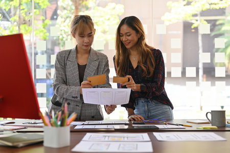 Asian female business office workers compare something with her adaptive media design on paperwork...