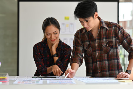 Young Creative Asian woman and man Ux Ui designer planning to create smartphone application.Website design, app development template, wireframe design concept.の写真素材