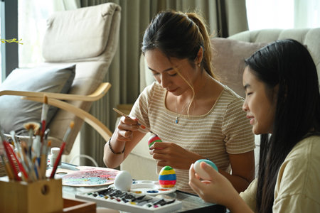 Asian female and child focused on painting Easter egg for special holiday. Getting readay for Easter holiday.の写真素材