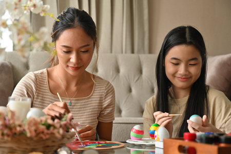 Lovely two Asian happily family while gathering at coffee table in living room for Easter eggs painting.の写真素材