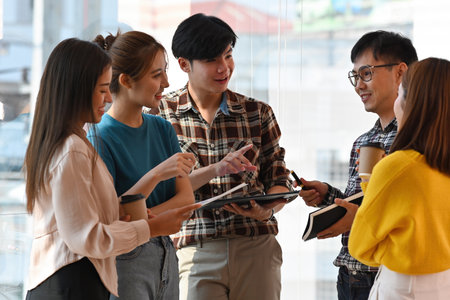 Group of young Asian business people working and communicating while standing at the modern office together. Full concentration at work. Business meeting. Business and financial concepts.の写真素材