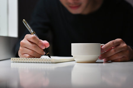 Close up of Asian businessman working on accounting and financial at night with a cup of coffee on desk. Business and financial concepts.の写真素材