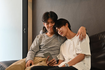 A couple o f LGBT using a smartphone and spending the day together at home, LGBT Lifestyle concept.の写真素材