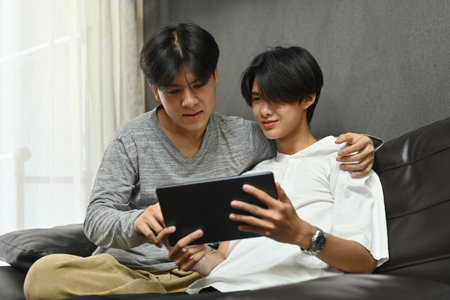 Gay couple having an enjoy moment with their digital tablet, LGBT couples and Everyday life at home...