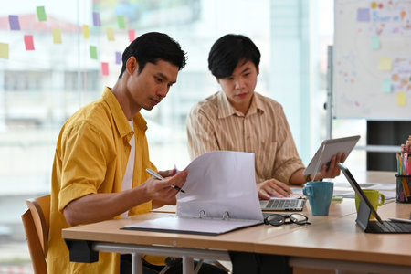 A portrait of handsome Asian businessmen working together on a laptop and having a discussion on...