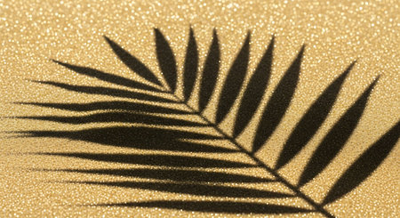 Palm leaf shadow on golden glitter background. Minimal concept.の写真素材