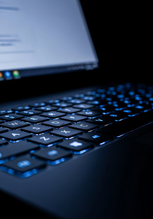 Close up of a laptop keyboard with blue light on a dark backgroundの写真素材