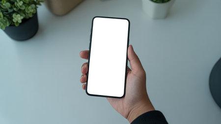 Mockup image of a hand holding black mobile phone with isolated screen on white backgroundの写真素材