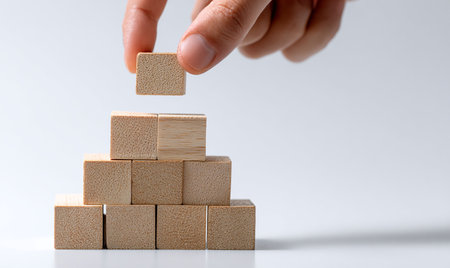 Hand arranging wood block stacking as step stair on white background, business growth concept.の写真素材