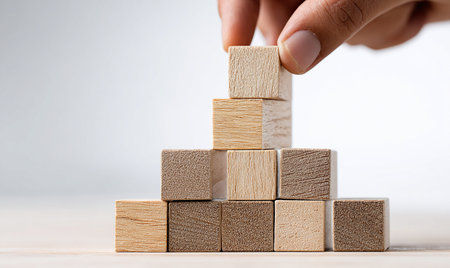 Hand arranging wood block stacking as step stair on white background, business growth conceptの写真素材