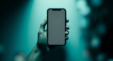 male hand holding a smartphone with a blank screen in the dark backgroundの写真素材